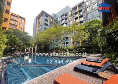 Swimming pool area with sun loungers in front of residential buildings