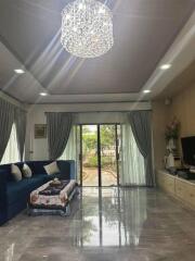 Spacious living room with a blue sofa, chandelier, and large windows