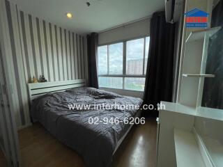 A cozy bedroom with a large window and a bed.