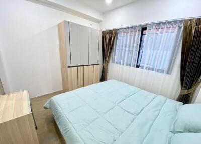 Modern bedroom with a bed, wardrobe, and window with curtains