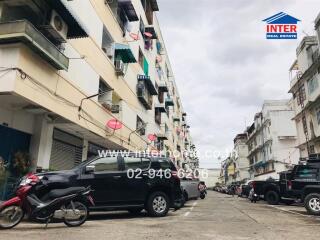 View of residential building exterior with parked vehicles