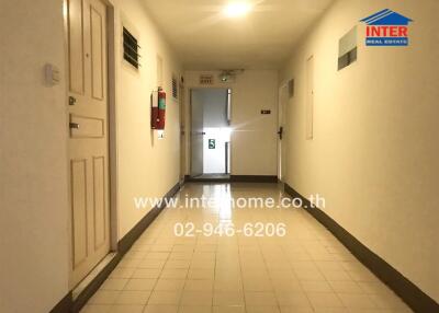 Hallway leading to apartment doors with safety and fire equipment visible