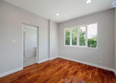 Empty bedroom with wooden floors and large windows
