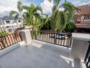 Balcony with railing, tiled floor, and view of neighborhood with houses and palm trees