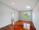 Spacious bedroom with polished wooden floors and large window