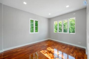 Spacious bedroom with hardwood floors and large windows