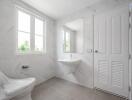 Modern bathroom with large windows, a wall-mounted sink, and a toilet