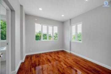 Spacious bedroom with wooden flooring and ample natural light