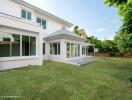 Exterior view of a modern two-story white house with a spacious backyard