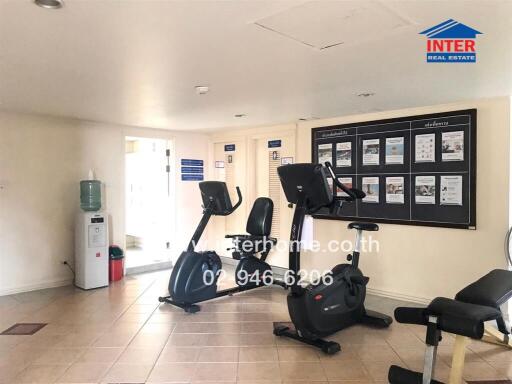 Fitness room with exercise equipment and informational board.