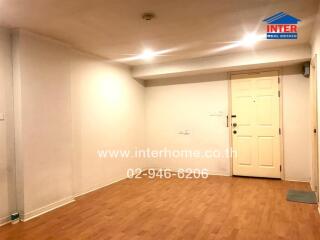 Spacious living area with wooden flooring and white walls