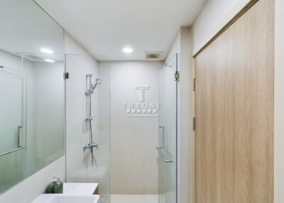 Modern bathroom with glass shower and wooden door