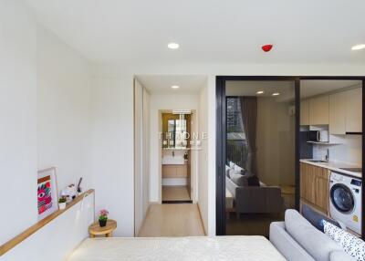 Main living area with bed, sofa, kitchenette, and hallway to bathroom