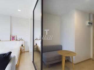 Modern bedroom with glass sliding door, couch, and a small table