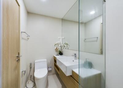 Modern bathroom with toilet, double sinks, and large mirror