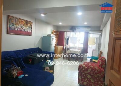 Cozy living room with blue sectional sofa, red patterned armchair, and dining table.