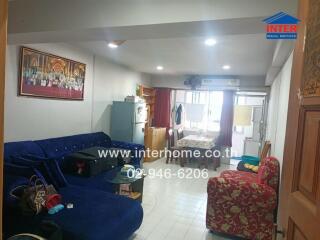 Cozy living room with blue sectional sofa, red patterned armchair, and dining table.