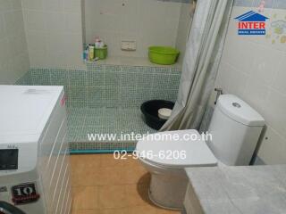 Bathroom with shower, washing machine, and toilet