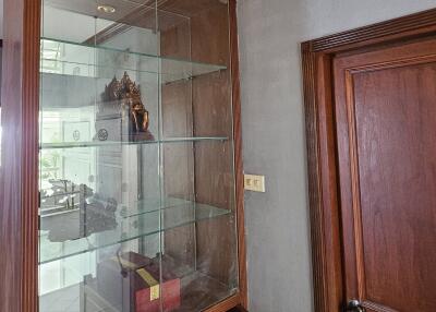 Wooden cabinet with glass shelves and a door in a living area