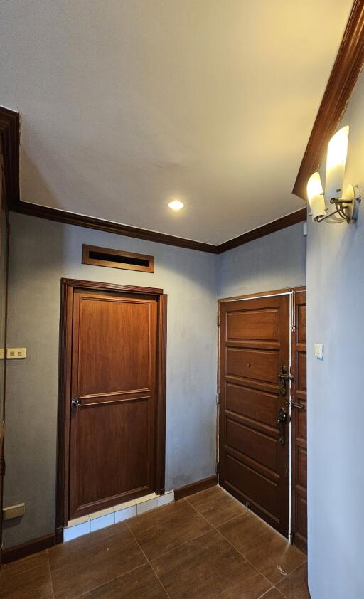 Photo of a residential entryway with wooden doors and tiled floor