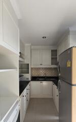 Modern kitchen with white cabinetry, black countertops, and stainless steel appliances