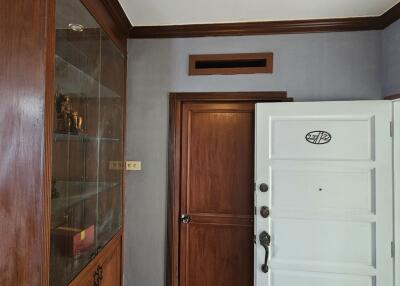 Entrance with wooden door and adjacent glass display cabinet