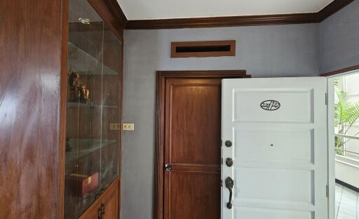 Entrance with wooden door and adjacent glass display cabinet