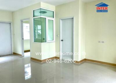 Spacious empty room with tiled flooring and multiple doors