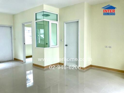 Spacious empty room with tiled flooring and multiple doors
