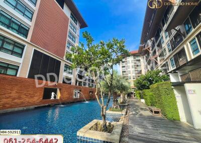 Outdoor view of a modern apartment complex with a swimming pool and tropical landscaping