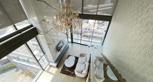 Spacious living room with large windows, chandelier, modern furniture, and city view