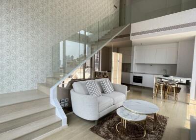 Modern duplex living area with open kitchen and staircase