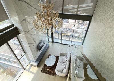 High view of a luxurious living room with large windows and a chandelier