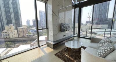 Modern living room with large windows, city view, marble accent wall, and a mounted television