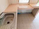 Simple kitchen setup with tiled counter, sink, and window