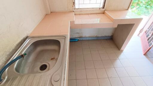 Simple kitchen setup with tiled counter, sink, and window