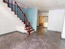 Spacious living area with tiled floor and wooden staircase