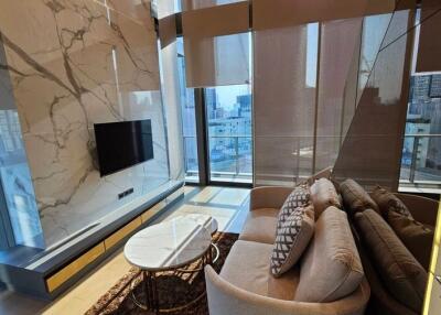 Modern living room with large windows, marble wall, and a comfortable couch