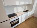 Modern minimalist kitchen with white cabinetry and wooden flooring