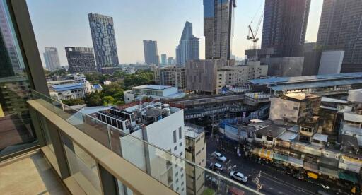 View from a balcony overlooking a bustling cityscape with high-rise buildings and a street below