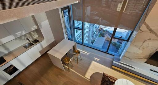 Modern kitchen with island and two stools, natural light through large windows