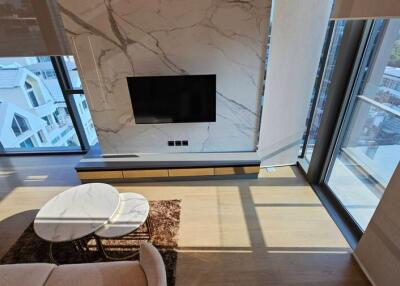 Living room with modern design featuring large windows, a wall-mounted TV, and a marble accent wall