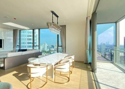 Modern living room with city view, large windows, and elegant dining area