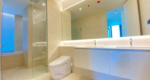 Modern bathroom with a large mirror, double sinks, and a walk-in shower
