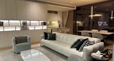 A modern living room with adjacent dining area, featuring contemporary furniture and lighting