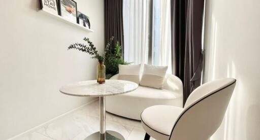 Modern living area with round white armchair, small marble table, and white chair with dark accent