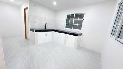 Modern kitchen with white cabinets, black countertops, and a large window