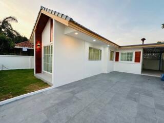 Front view of a modern single-story house with a gray tiled driveway and manicured lawn