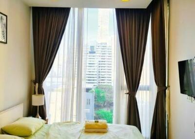 City view bedroom with large windows, double bed, bedside table, and wall-mounted TV