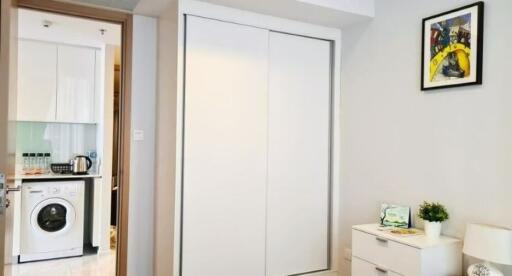 Modern bedroom with large wardrobe and view into adjacent laundry/kitchen area